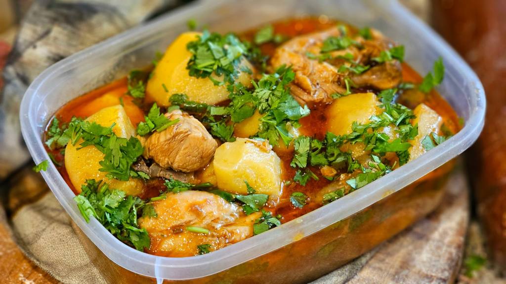 A mouth-watering chicken stew with potatoes and herbs in a transparent container.
