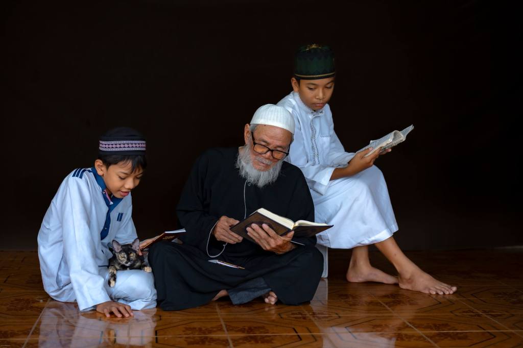 Three generations engaged in reading religious texts, highlighting cultural tradition and learning.