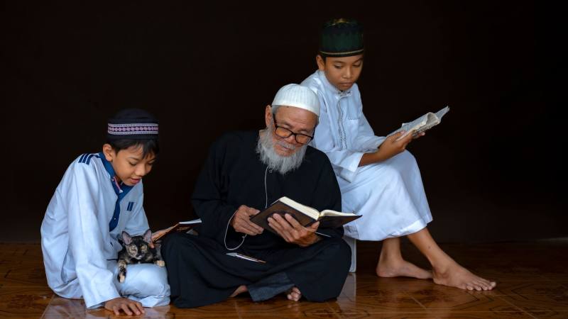 Three generations engaged in reading religious texts, highlighting cultural tradition and learning.